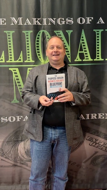 Reader holding The Purpose-Driven Business Builder's Blueprint at Sticker Shock